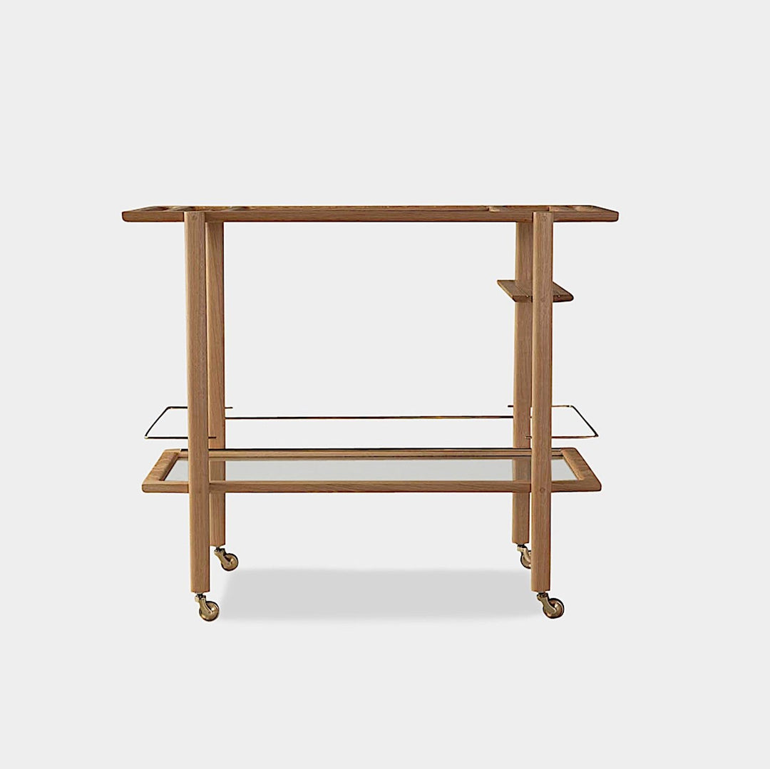 The BAR Cart from Earl Home is a solid wood bar cart on wheels with exquisite hand-cut joinery, featuring two shelves: a robust wood top and an elegant lower shelf made of tempered glass panels.