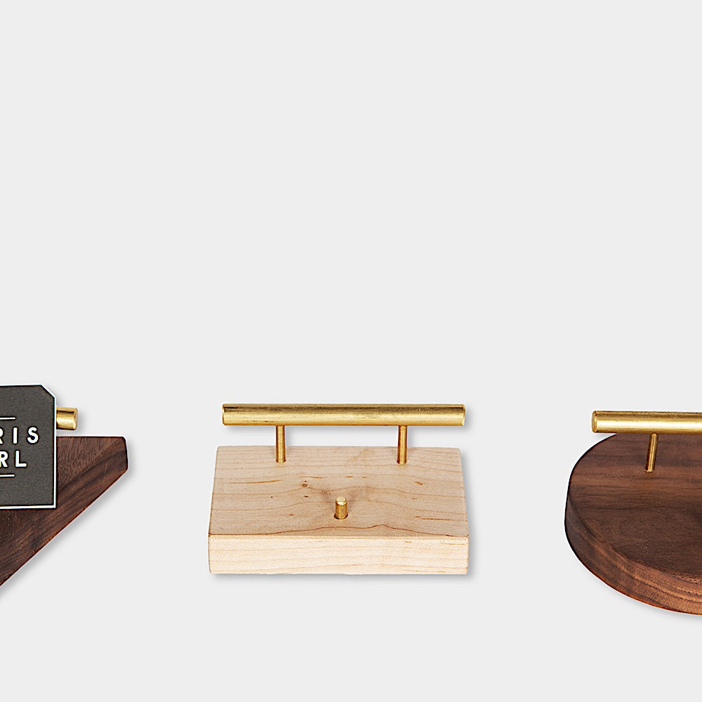 The BUSINESS Card Holder, expertly crafted by Earl Home from wood and brass, showcases a card with "CHRIS EARL." This elegant accessory can be customized to perfectly fit any desk or office setting.