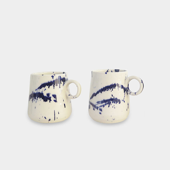 The TAPERED Mug by Earl Home is a hand-thrown white ceramic piece, showcasing a bold dark blue brush stroke and a round handle against a light gray background.