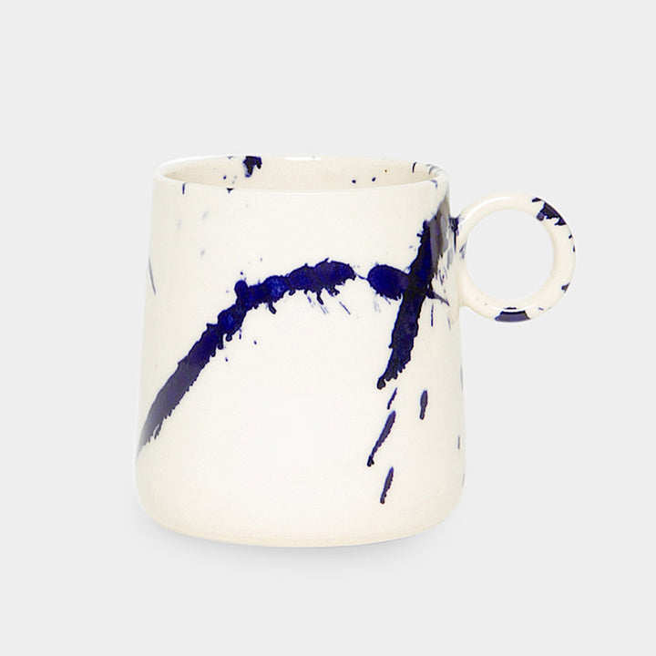 The TAPERED Mug by Earl Home is a hand-thrown white ceramic piece, showcasing a bold dark blue brush stroke and a round handle against a light gray background.