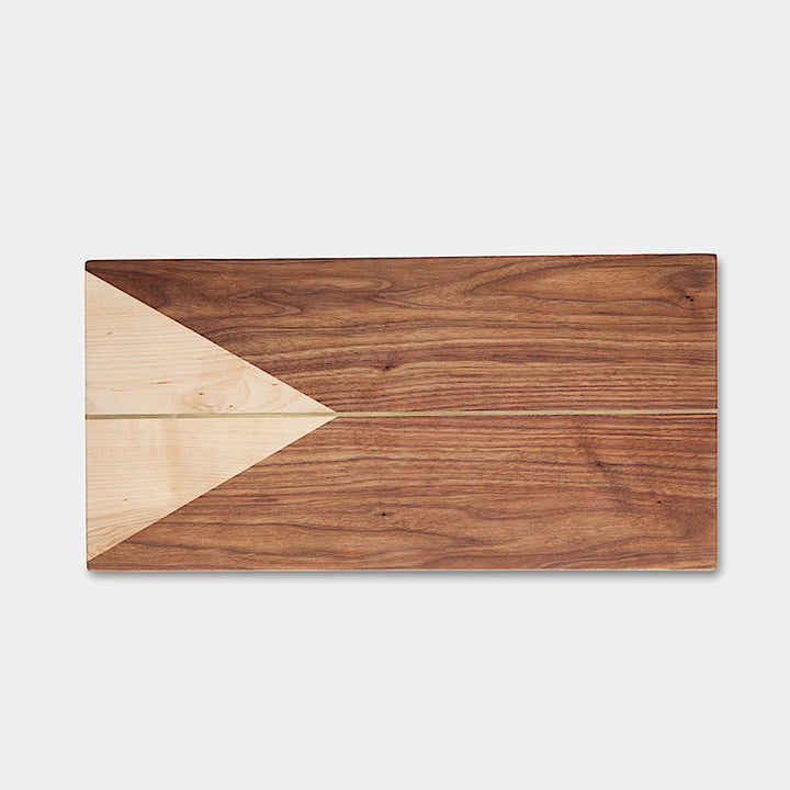 The RECTANGLE Cheese Board by Earl Home is a handcrafted serving board featuring a natural wood grain and accented with an off-center pale triangle on the left, ideal for elegant entertaining.