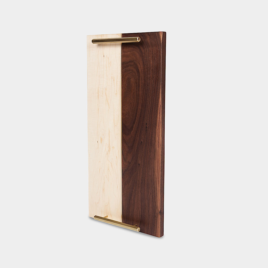 The RECTANGLE Service Tray by Earl Home is a handcrafted, two-tone wooden serving board with elegant brass handles, featuring a light and dark wood design akin to a classic brass tray.