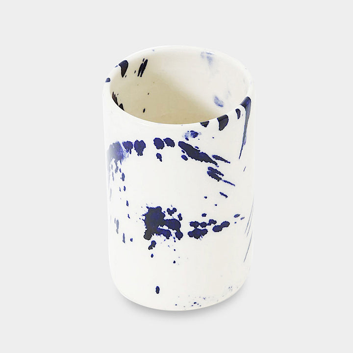 Earl Home's TUMBLR set includes four white ceramic cups with captivating blue brush stroke splatter designs that showcase their hand-thrown artistry.