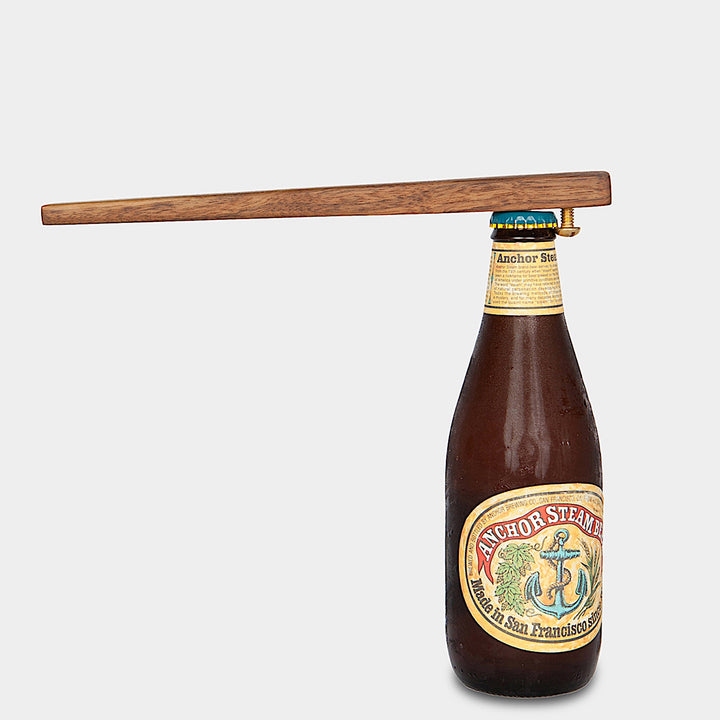 A bottle of Anchor Steam beer is topped with an Earl Home WOOD + BRASS Bottle Opener, combining style and practicality.