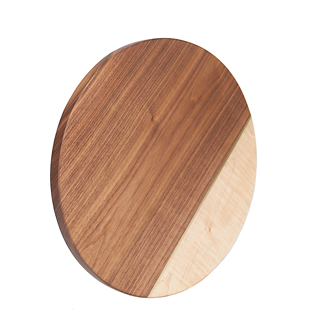 The CIRCLE Cheese Board by Earl Home is a stylish essential for entertaining, doubling as a handcrafted cheeseboard with its two-tone design featuring a diagonal divide of dark walnut and light maple. Ideal for elevating your presentations.