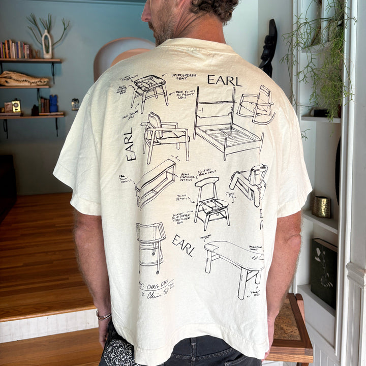 Man wearing a white t-shirt with black text and graphics in a room.