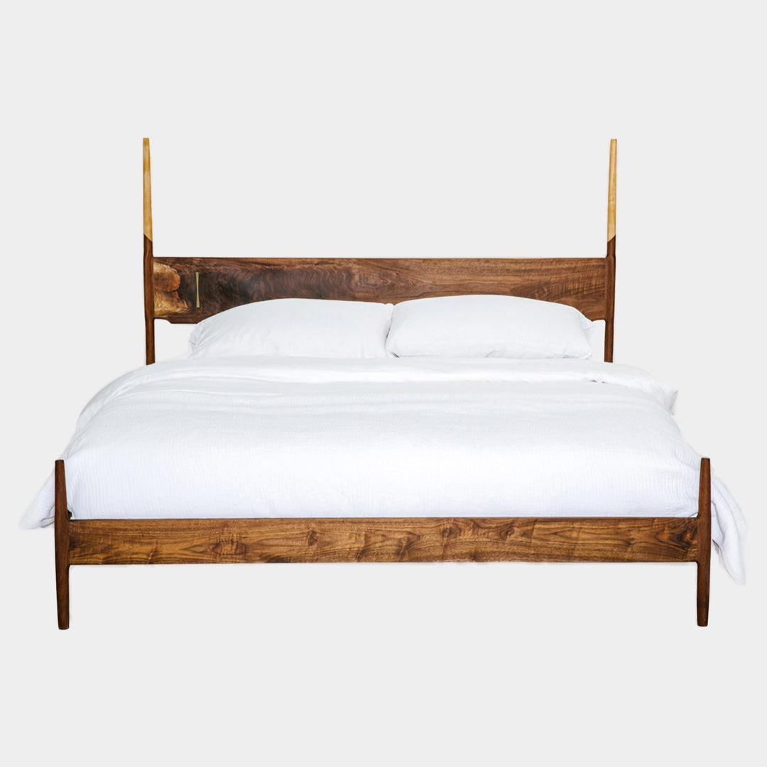 The DANSK Bed by Earl Home features a solid wood frame with a tall headboard and luxurious white bedding, creating your perfect sanctuary. Crafted in walnut, it exemplifies quality and is handmade to order.