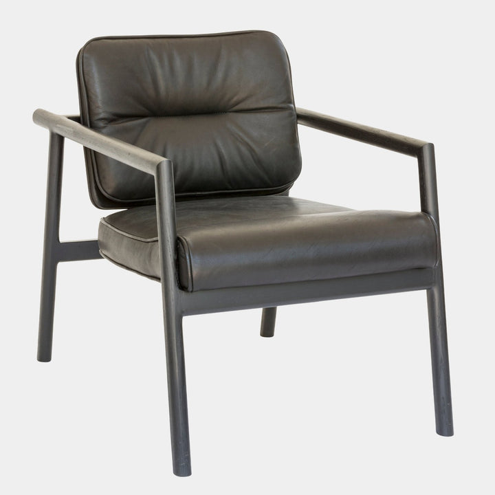 The MORESBY Lounge Chair by Earl Home is a modern, handmade piece featuring a sleek dark frame and a custom upholstered black leather cushion.