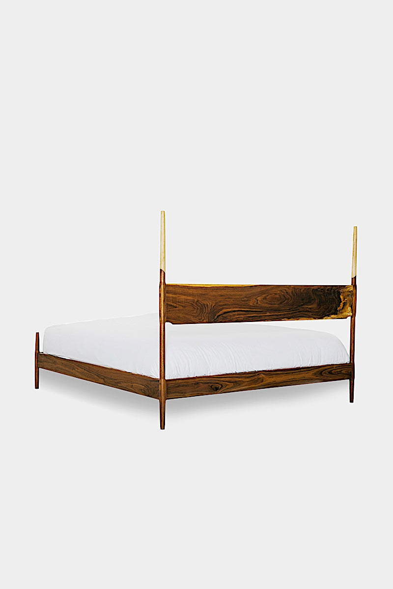 The DANSK Bed by Earl Home features a solid wood frame with a tall headboard and luxurious white bedding, creating your perfect sanctuary. Crafted in walnut, it exemplifies quality and is handmade to order.