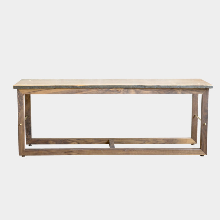 The Earl Home Walnut HAROLD Bench is a handcrafted masterpiece with a simple rectangular design and an open frame, featuring elegant walnut wood and brass detailing.