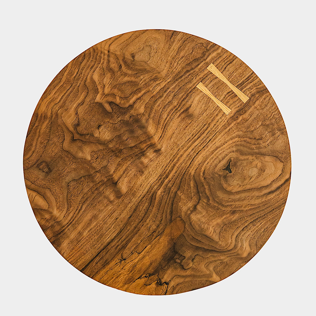 The CIRCLE Cutting Board by Earl Home features a round wooden design with a natural grain pattern and two light-colored surface inserts.