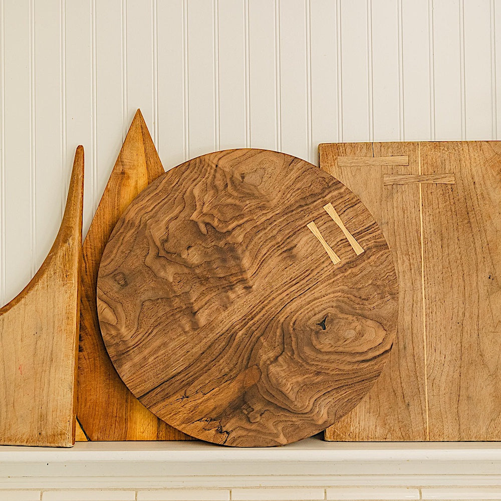 The CIRCLE Cutting Board by Earl Home features a round wooden design with a natural grain pattern and two light-colored surface inserts.