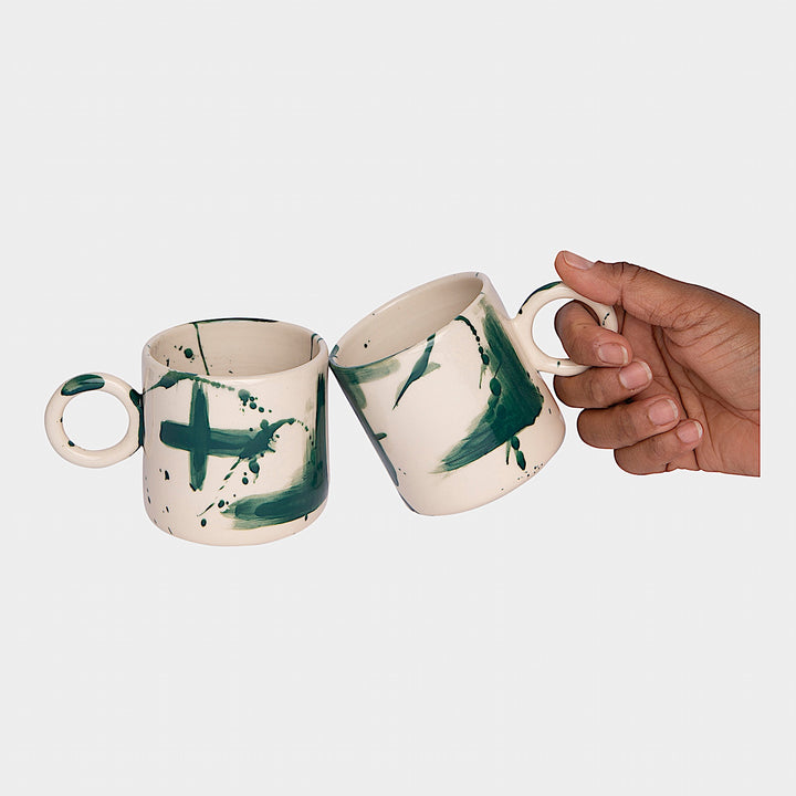 Earl Home's CIRCLE Mug is a hand-thrown white ceramic mug with black brush stroke splatters and a round handle.