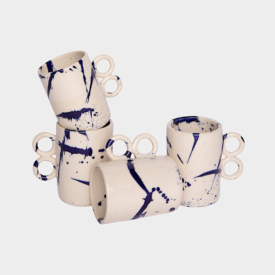 The Earl Home DOUBLE Handle Mug set includes two brown ceramic mugs, each featuring a unique round handle and white abstract patterns. Hand-thrown for artisanal charm, these mugs are perfect for those who appreciate the delicate artistry of ceramic craftsmanship.