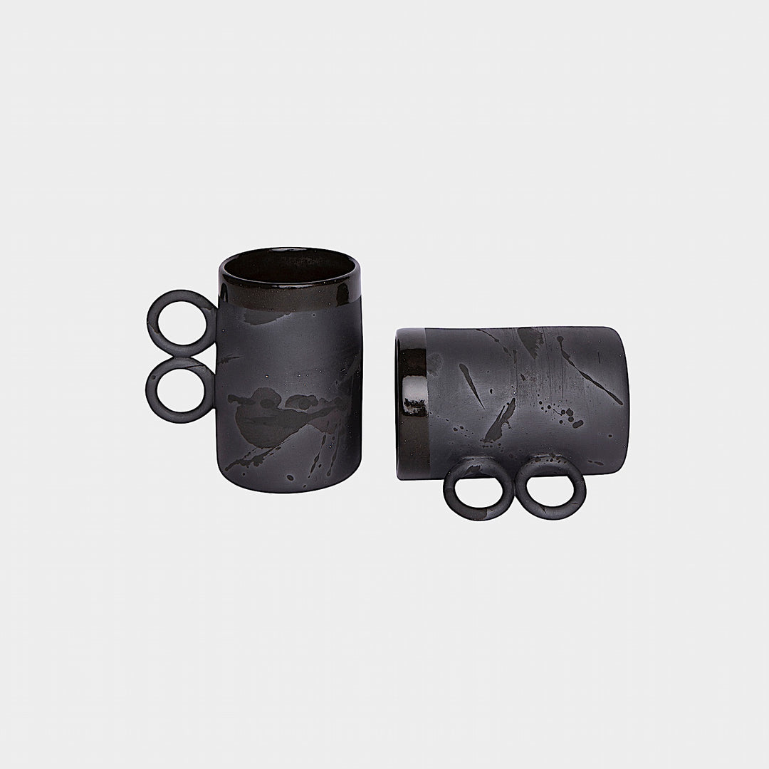 The Earl Home DOUBLE Handle Mug set includes two brown ceramic mugs, each featuring a unique round handle and white abstract patterns. Hand-thrown for artisanal charm, these mugs are perfect for those who appreciate the delicate artistry of ceramic craftsmanship.