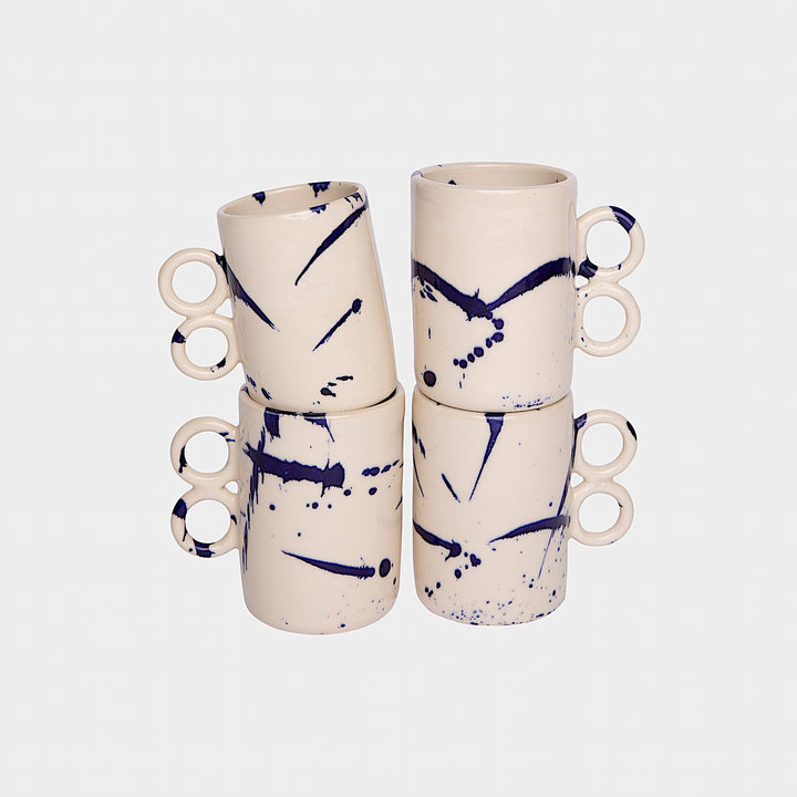 The Earl Home DOUBLE Handle Mug set includes two brown ceramic mugs, each featuring a unique round handle and white abstract patterns. Hand-thrown for artisanal charm, these mugs are perfect for those who appreciate the delicate artistry of ceramic craftsmanship.