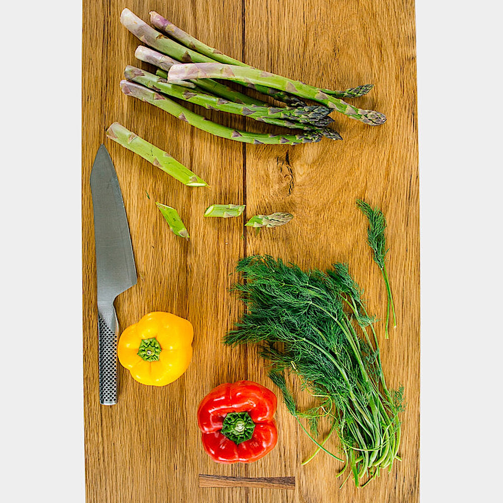 The LIVE EDGE Cutting Board by Earl Home, featuring a stunning live-edge design and natural grain finish, stands upright against a light gray background.