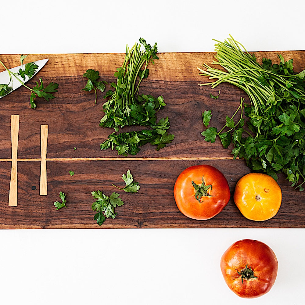 The Rectangle Cutting Board by Earl Home is a wooden board featuring a natural oak grain pattern with two parallel walnut inlays near one end.