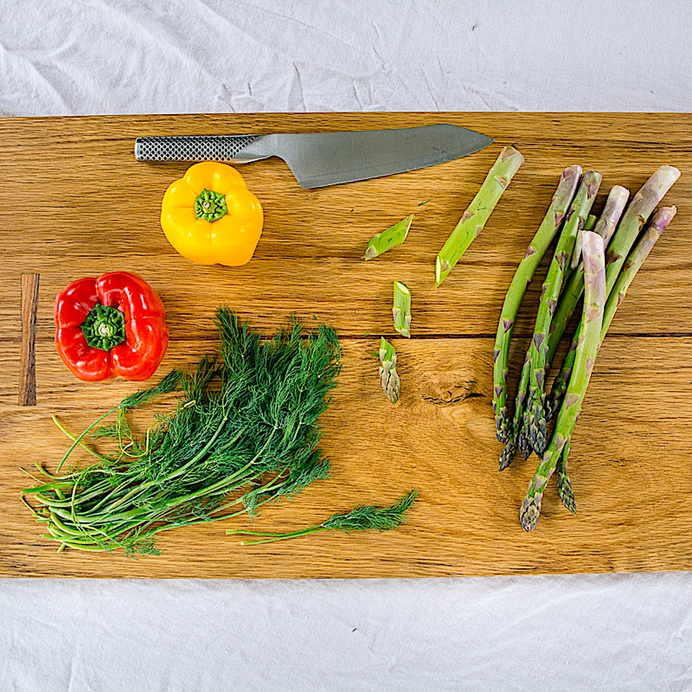 The Rectangle Cutting Board by Earl Home is a wooden board featuring a natural oak grain pattern with two parallel walnut inlays near one end.