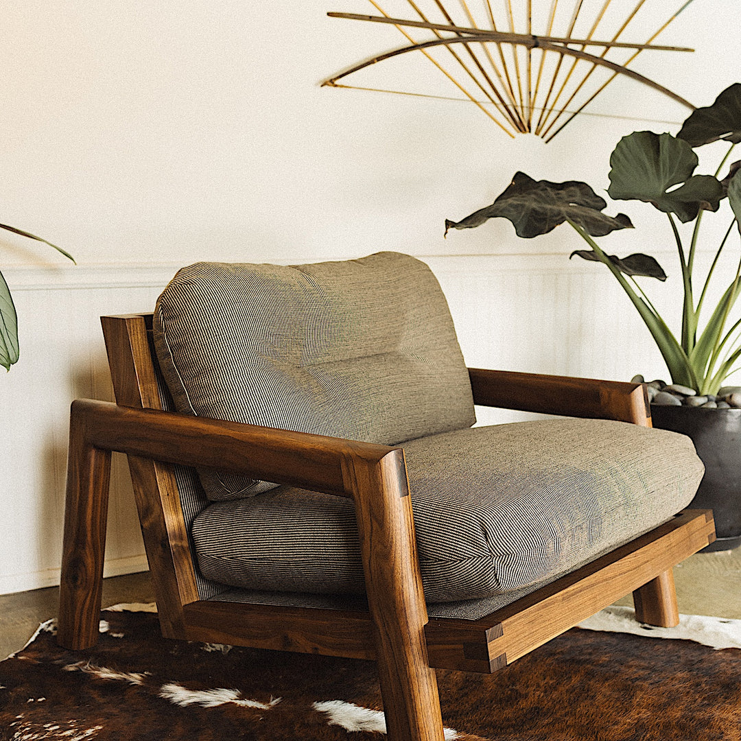 The Earl Home Walnut TAMBU Lounge Chair boasts olive leather upholstery, a sturdy walnut frame, and cushioned seat and backrest.