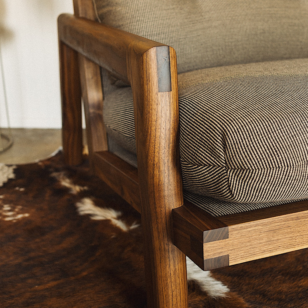 The Earl Home Walnut TAMBU Lounge Chair boasts olive leather upholstery, a sturdy walnut frame, and cushioned seat and backrest.