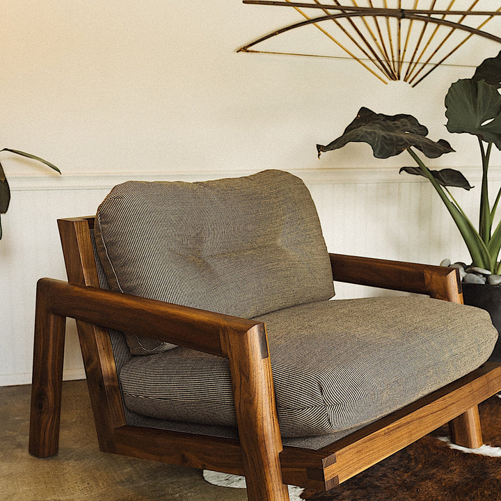 The Earl Home Walnut TAMBU Lounge Chair boasts olive leather upholstery, a sturdy walnut frame, and cushioned seat and backrest.