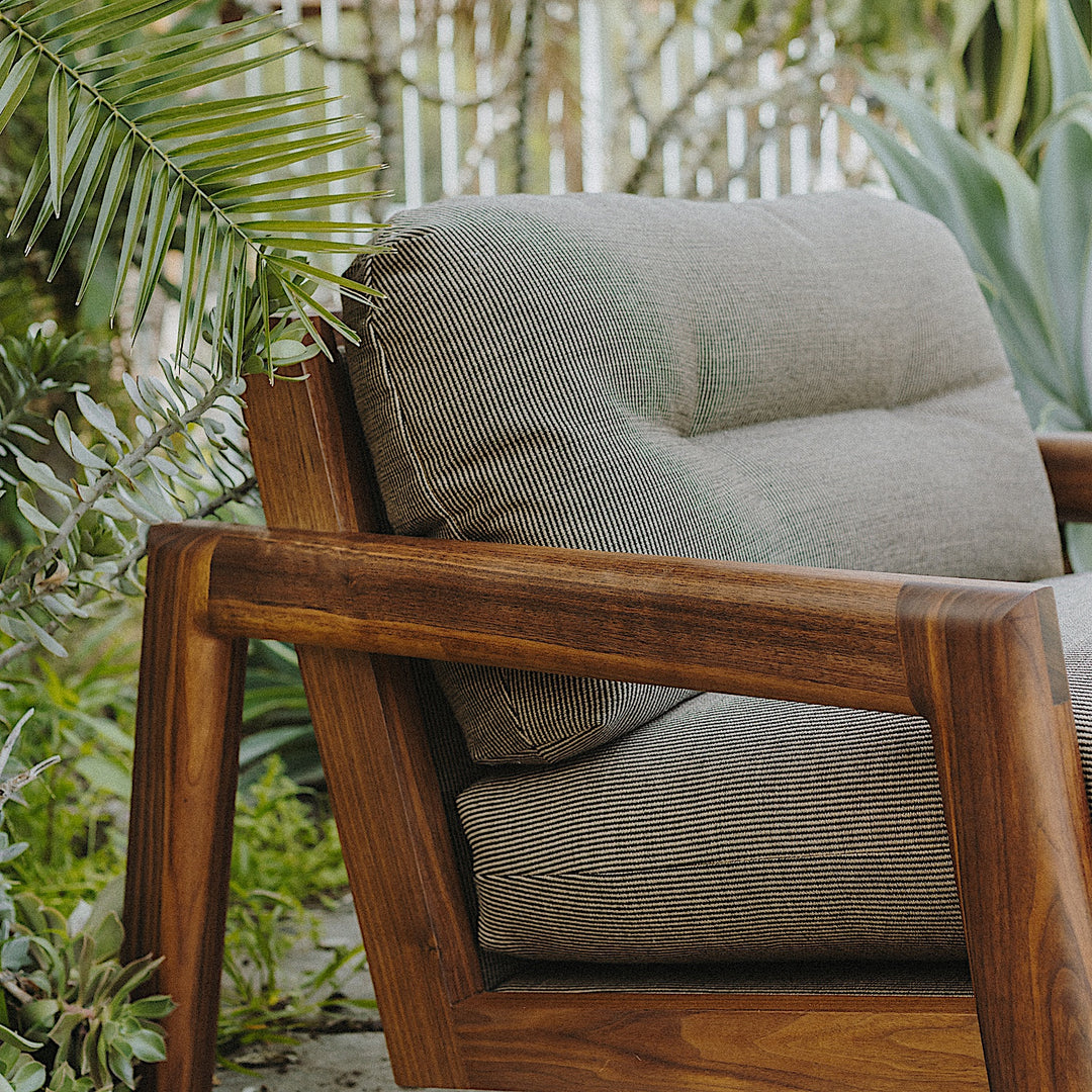 The Earl Home Walnut TAMBU Lounge Chair boasts olive leather upholstery, a sturdy walnut frame, and cushioned seat and backrest.