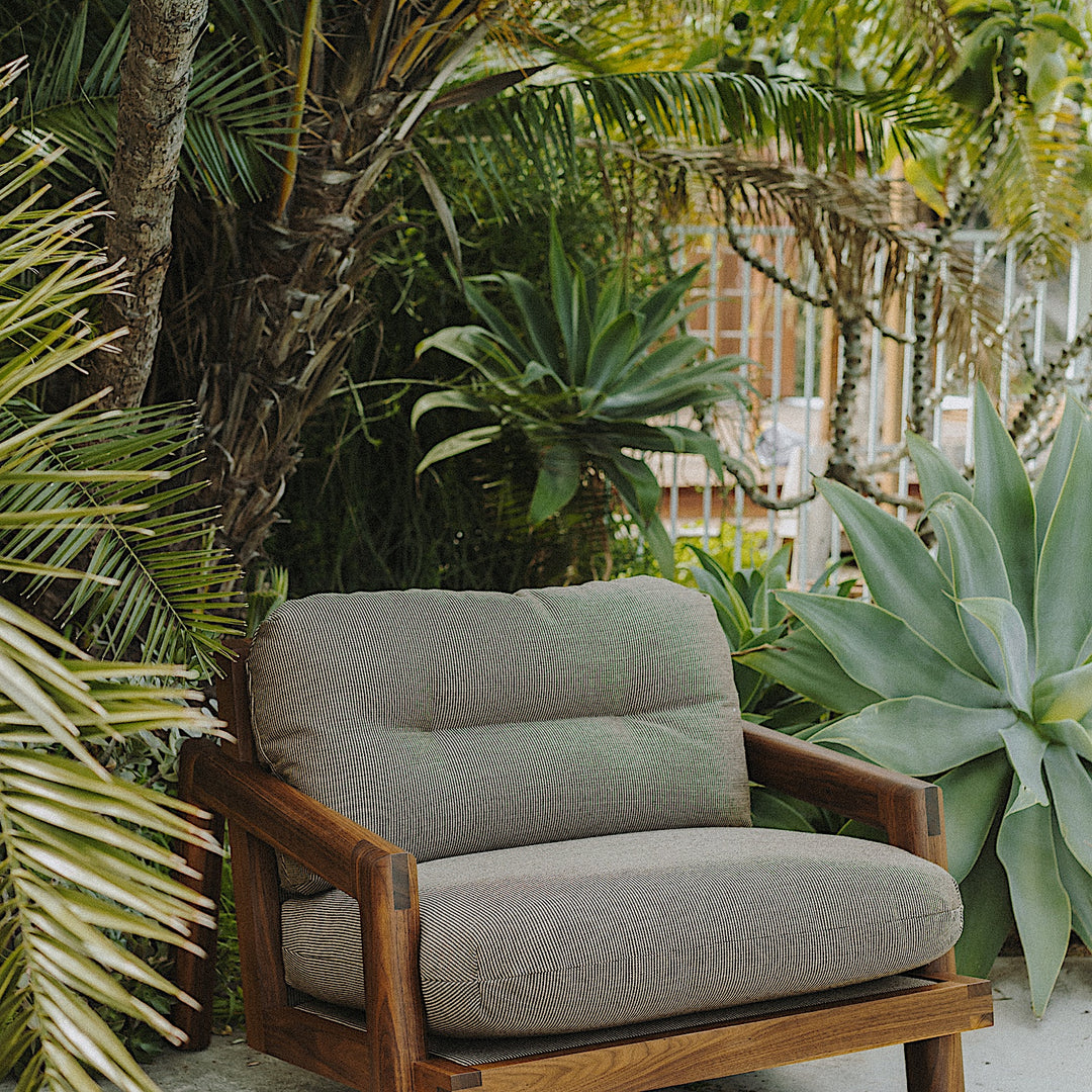 The Earl Home Walnut TAMBU Lounge Chair boasts olive leather upholstery, a sturdy walnut frame, and cushioned seat and backrest.