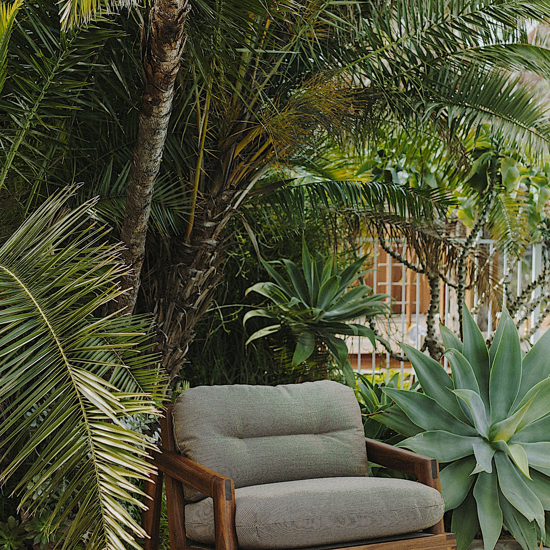 The Earl Home Walnut TAMBU Lounge Chair boasts olive leather upholstery, a sturdy walnut frame, and cushioned seat and backrest.