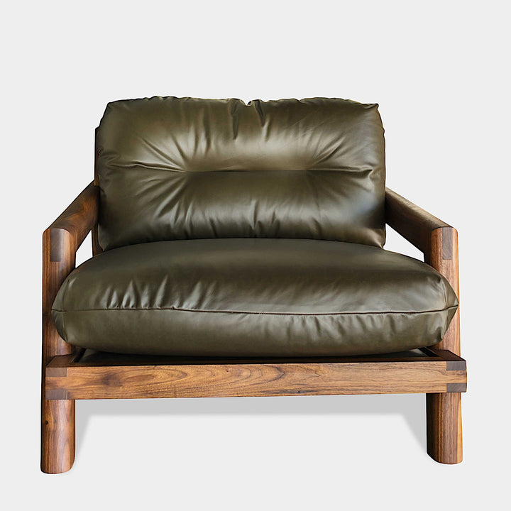 The Earl Home Walnut TAMBU Lounge Chair boasts olive leather upholstery, a sturdy walnut frame, and cushioned seat and backrest.