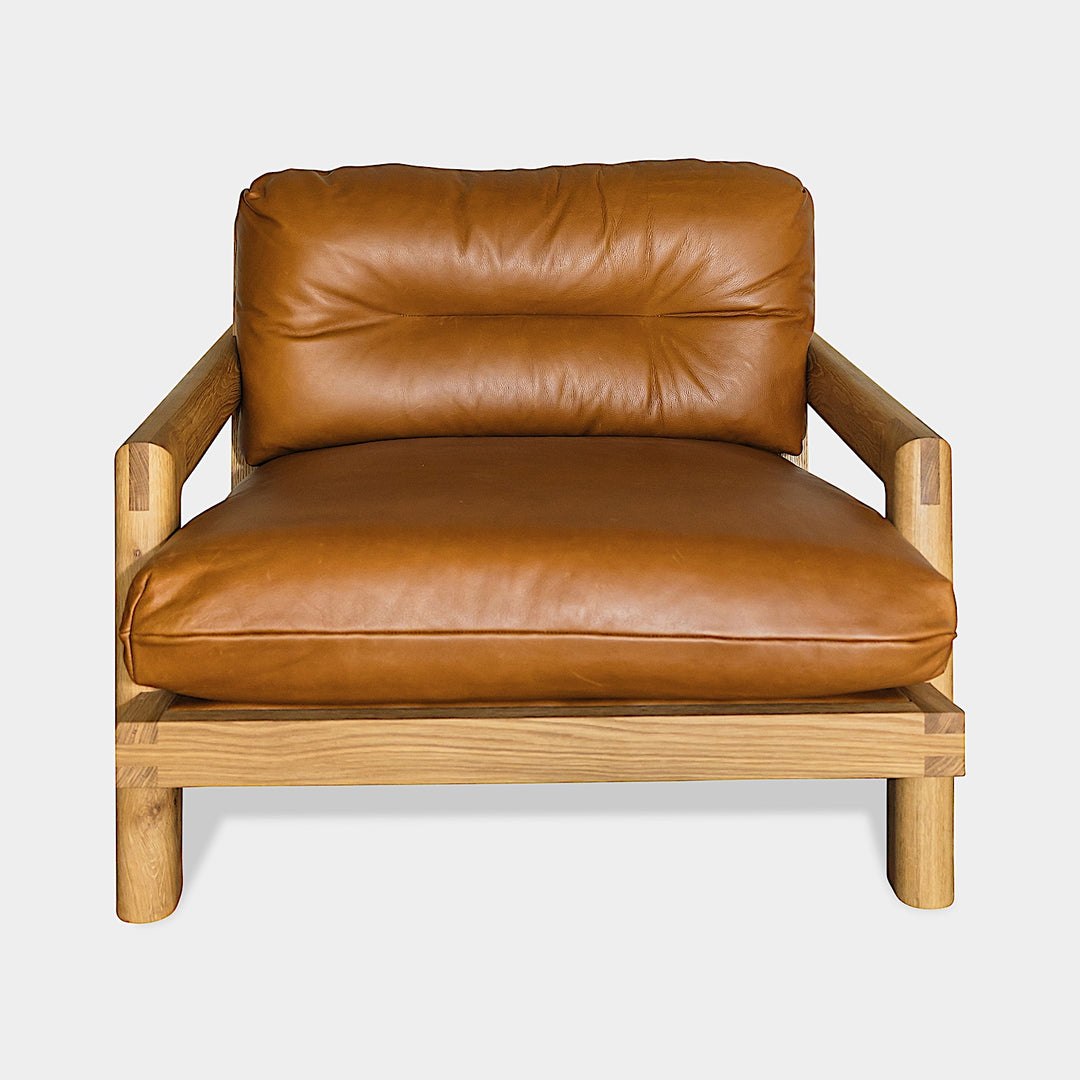 The Earl Home White Oak TAMBU Lounge Chair boasts camel leather upholstery, a sturdy oak frame, and plush down cushioned seat and backrest gives the ultimate cozy hygge vibe.