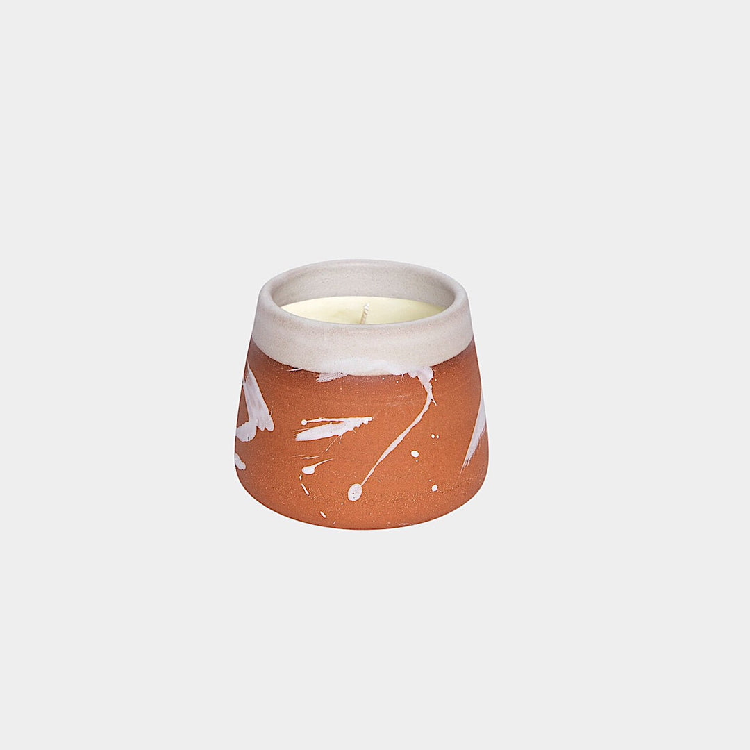 The Earl Home CANDLE is a white ceramic votive with a black splatter pattern, featuring an unlit cardamom-scented candle, set against a gray background.