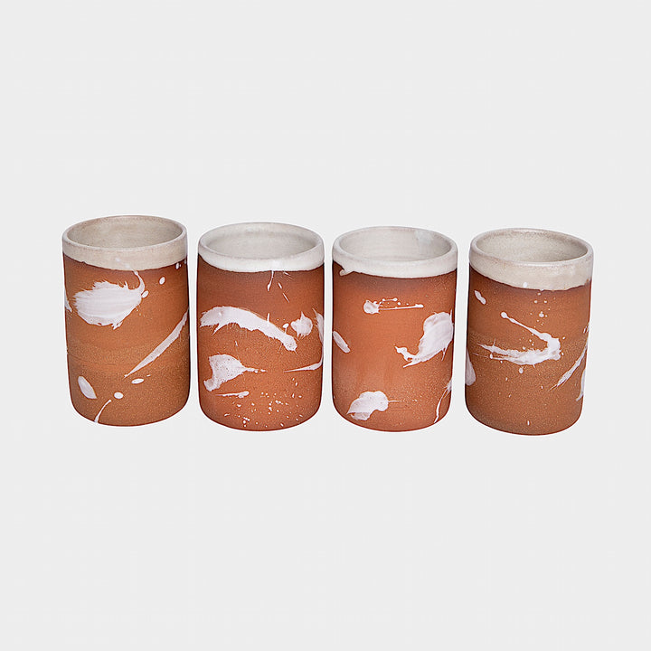 Four EARL Cups from Earl Home, featuring hand-thrown brown ceramic with unique white splashes, are arranged in a row against a plain background.