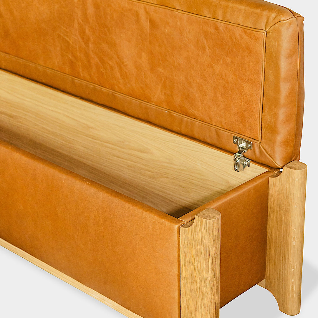 The Earl Home KABOT Storage Trunk is a stylish and practical piece with tan leather upholstery. It features an open lid that reveals a wooden interior with hinged supports, combining elegance and functionality.