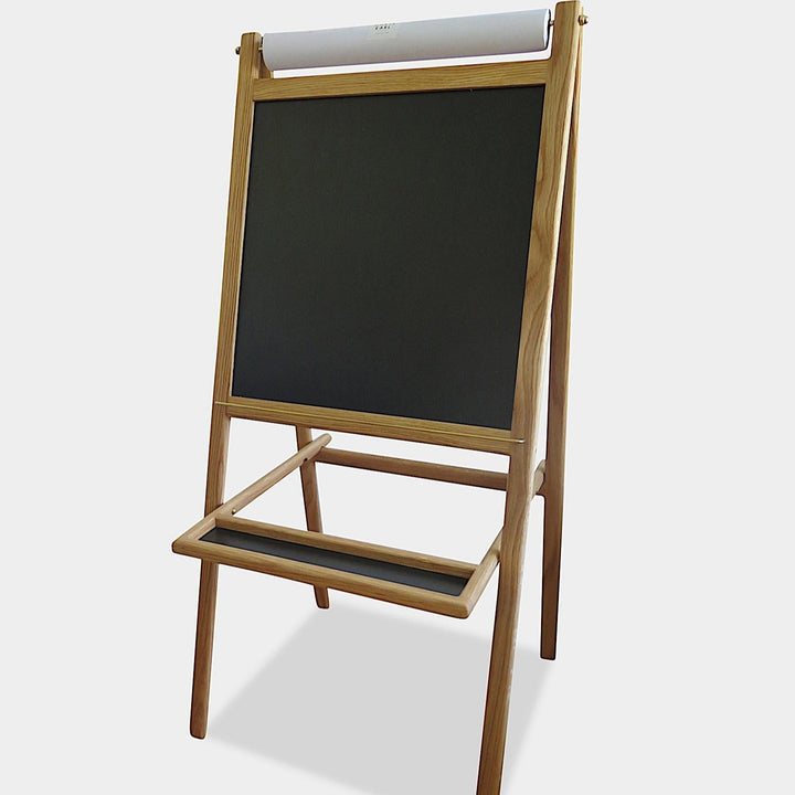 The KIDS Easel by Earl Home is a freestanding kids' easel made from sustainably sourced hardwood, featuring a chalkboard surface and a paper roll at the top.