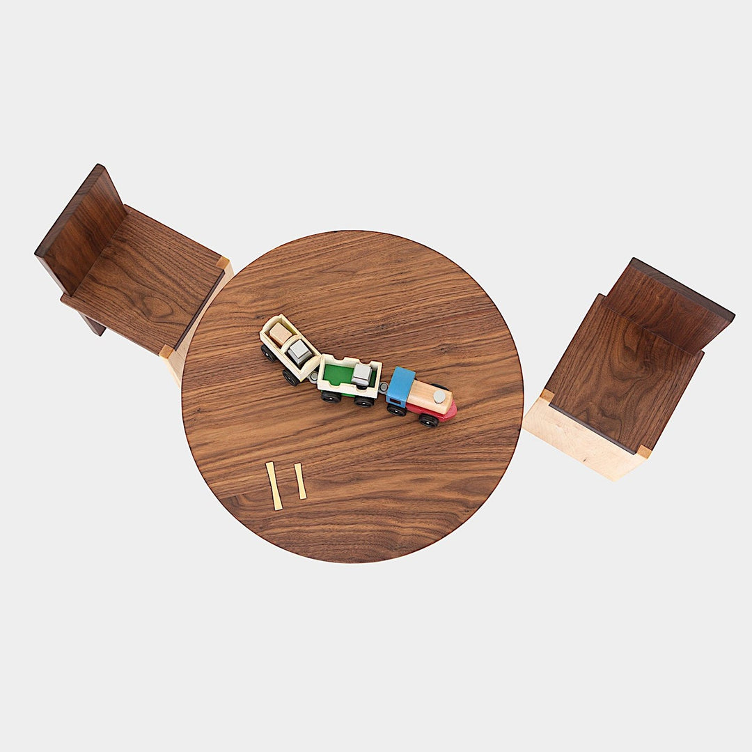 A top view showcases the Earl Home KIDS Set, featuring a custom, round wooden table made from sustainably sourced American hardwood. Two rectangular chairs are ideally positioned on opposite sides for a kid's table setup.