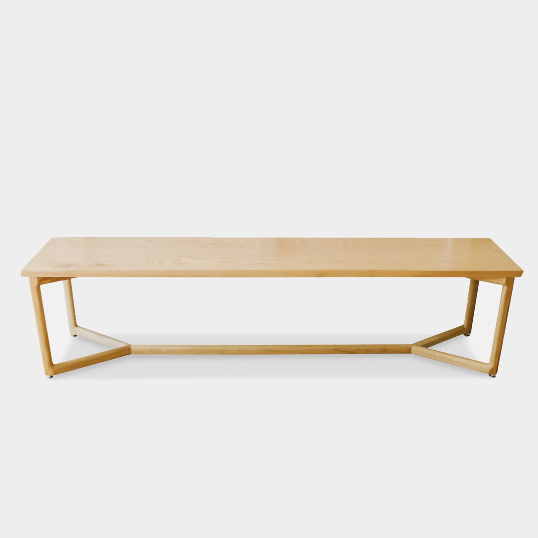 The WOLF Bench by Earl Home is a long, handcrafted piece with a light finish and angular metal legs that highlight the beauty of solid wood.