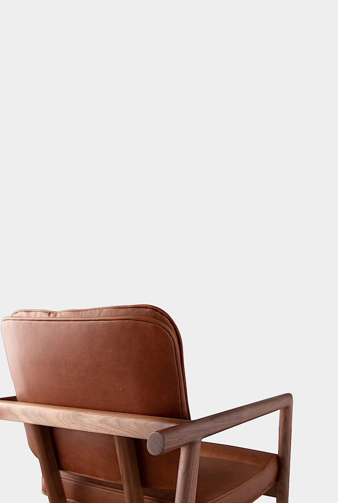 The MORESBY Captain Chair by Earl Home is hand-made with a custom upholstered seat in rich brown leather and solid wood, set against a white background.