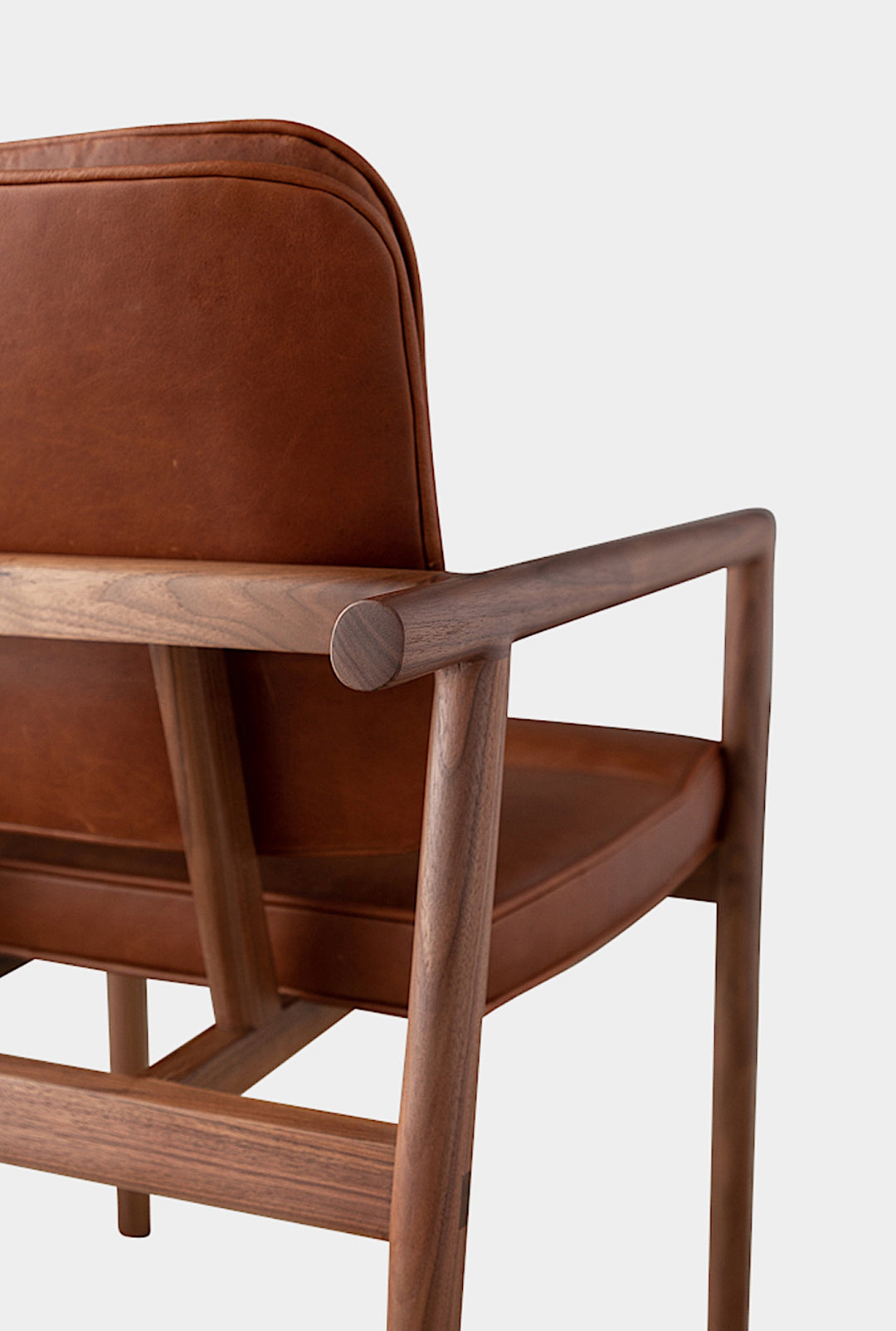 The MORESBY Captain Chair by Earl Home is hand-made with a custom upholstered seat in rich brown leather and solid wood, set against a white background.