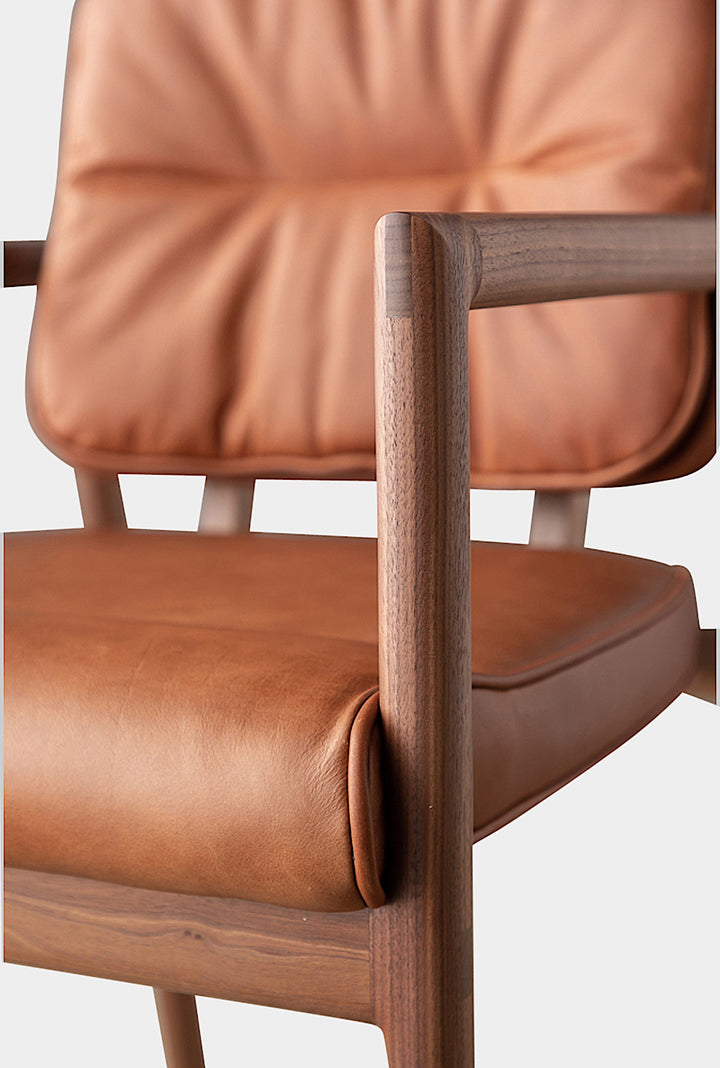 The MORESBY Captain Chair by Earl Home is hand-made with a custom upholstered seat in rich brown leather and solid wood, set against a white background.