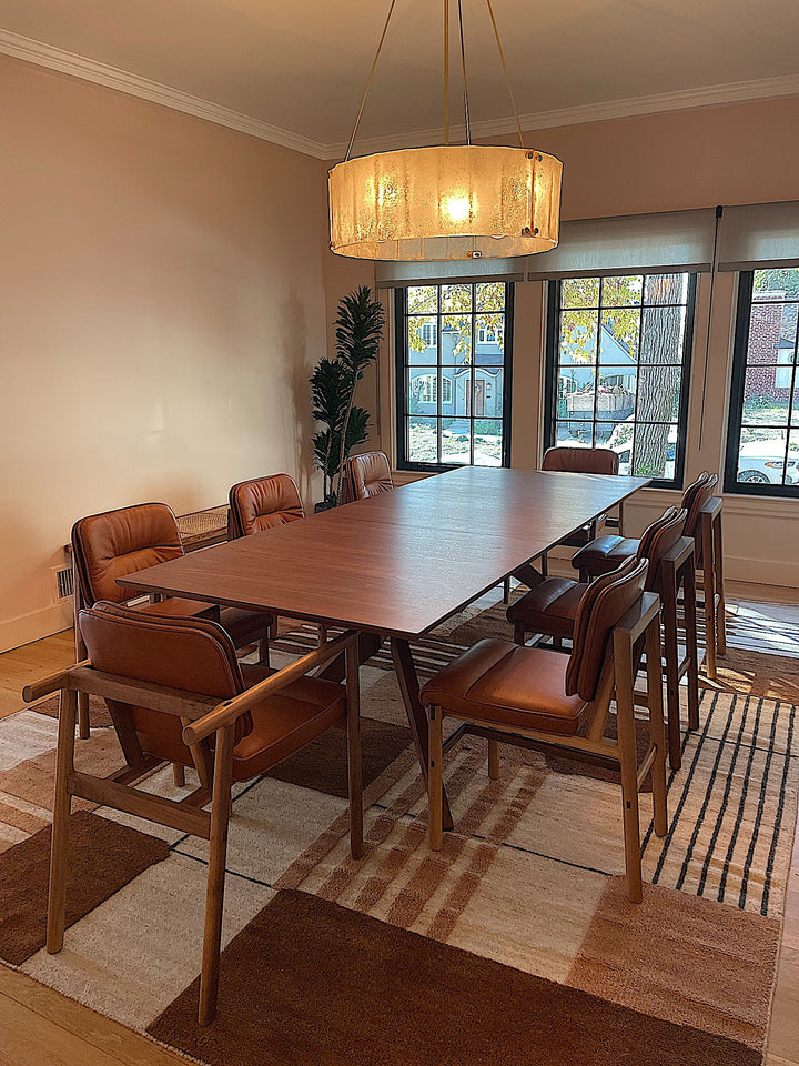 The MORESBY Dining Chair by Earl Home features a custom upholstered black leather seat and backrest, elegantly crafted on a solid wood frame with simple, angular lines.