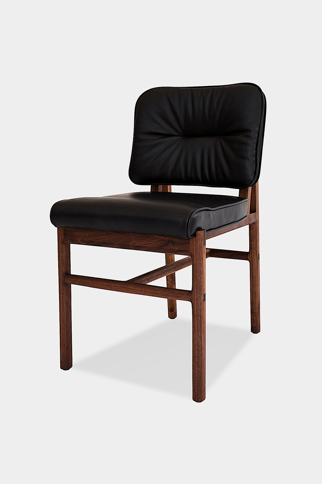 The MORESBY Dining Chair by Earl Home features a custom upholstered black leather seat and backrest, elegantly crafted on a solid wood frame with simple, angular lines.