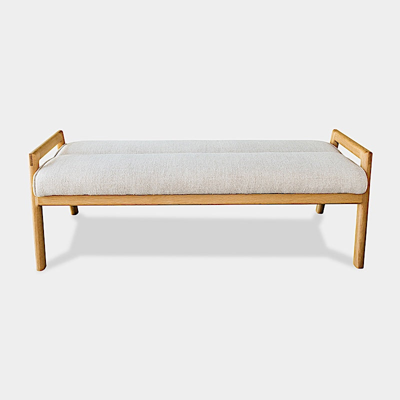 The Earl Home MORESBY Bench highlights a plush light beige cushion on solid wood, featuring clean lines and a minimalist design against a plain background.