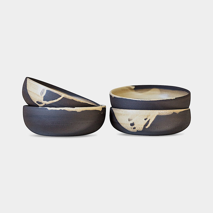 The Earl Home PASTA Bowl set includes four stylish white ceramic bowls featuring black abstract splatter designs. Each unique, hand-thrown piece is dishwasher safe, perfect for adding a distinct touch to your kitchen collection.