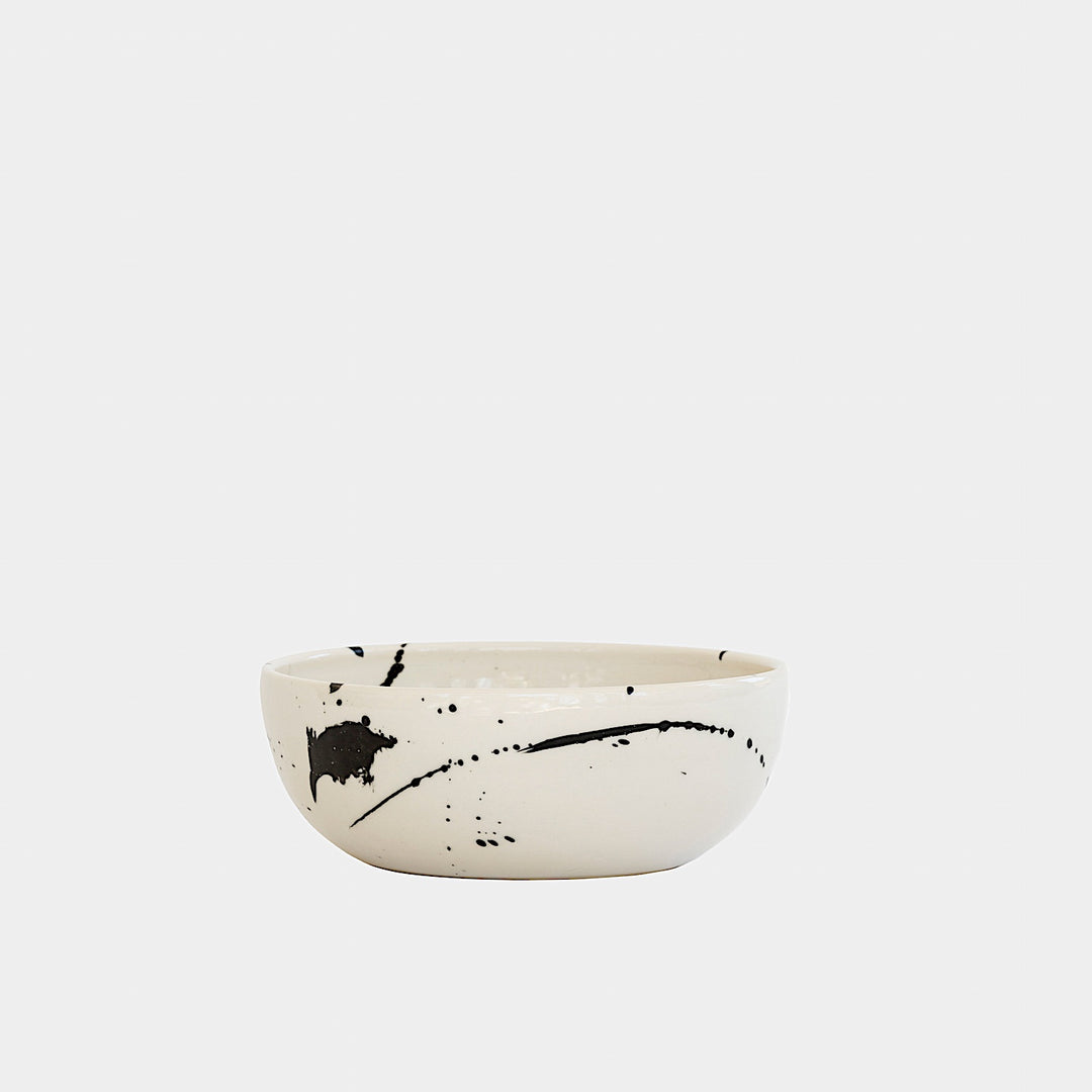 The Earl Home PASTA Bowl set includes four stylish white ceramic bowls featuring black abstract splatter designs. Each unique, hand-thrown piece is dishwasher safe, perfect for adding a distinct touch to your kitchen collection.