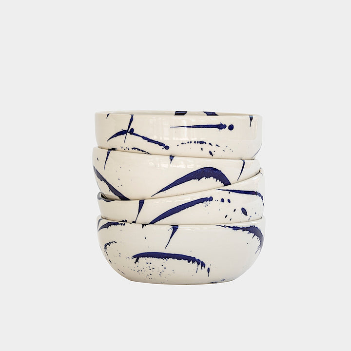 The Earl Home PASTA Bowl set includes four stylish white ceramic bowls featuring black abstract splatter designs. Each unique, hand-thrown piece is dishwasher safe, perfect for adding a distinct touch to your kitchen collection.