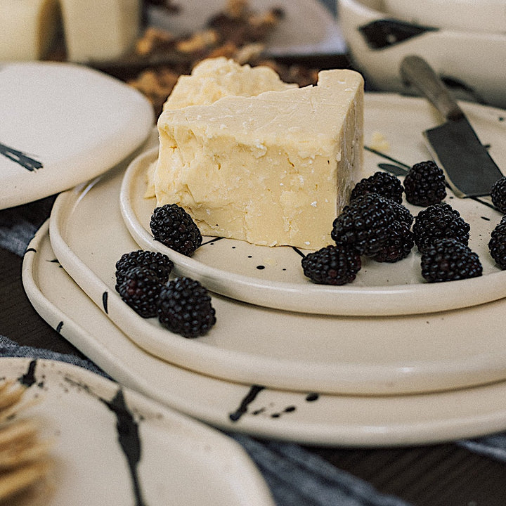 The Earl Home PLATES feature a round ceramic design with a white base and two intersecting dark blue splatter patterns. They are both dishwasher and microwave safe.