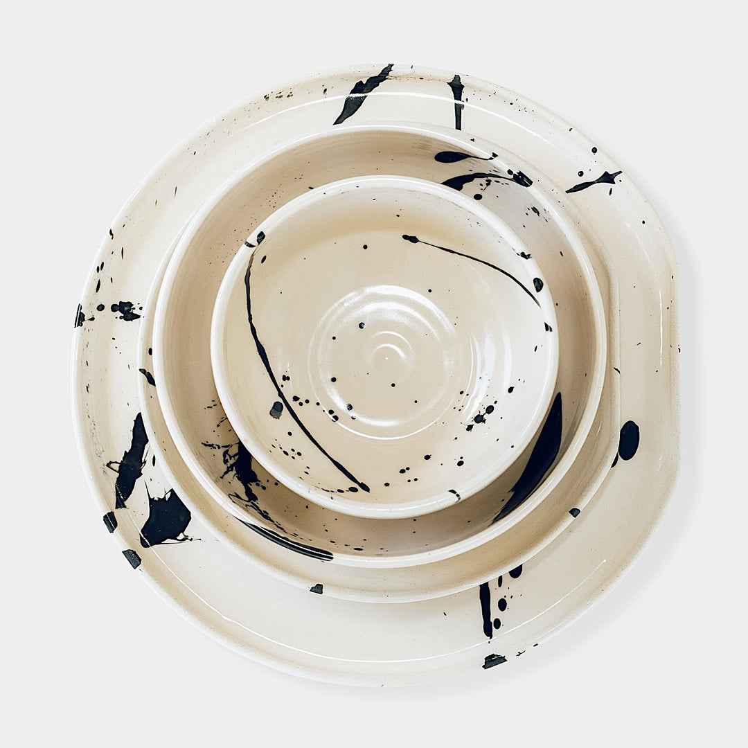 The Earl Home PLATES feature a round ceramic design with a white base and two intersecting dark blue splatter patterns. They are both dishwasher and microwave safe.