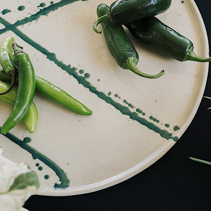 The Earl Home PLATES feature a round ceramic design with a white base and two intersecting dark blue splatter patterns. They are both dishwasher and microwave safe.