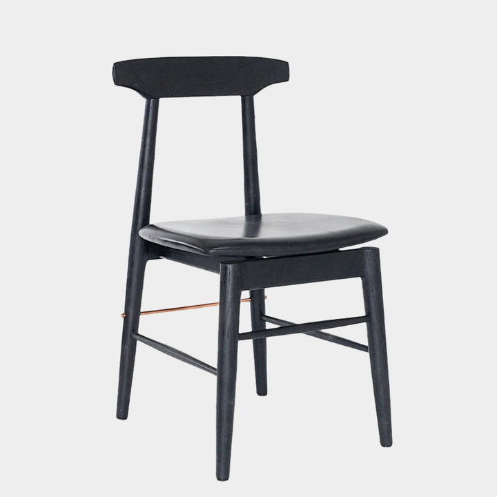 The Earl Home SABLE Dining Chair features a hand-made, black wooden design with a curved backrest and four legs. Its flat seat exemplifies minimalist elegance, crafted from solid wood for lasting durability.